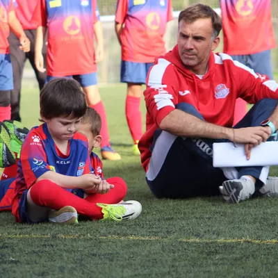 Un entrenador de l’EDFOR ajupit al costat d’un jugador petit